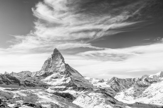 Fototapeta Monochrome view on snowy Matterhorn and other mountains with dramatic sky with clouds, Switzerland