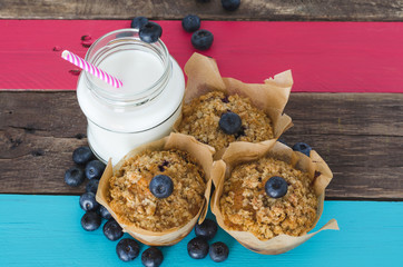 Cranberry muffins with milk on wooden background.
