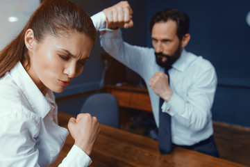 Obraz premium Male and female co workers imitate fighting while in office. Compete about project. Fight of genders concept.