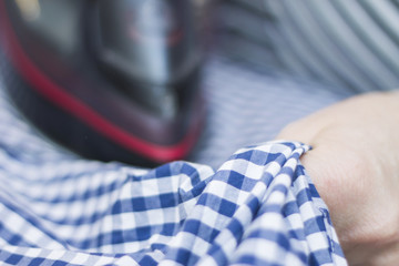 Housewife ironing a casual clothes on the ironing board closeup