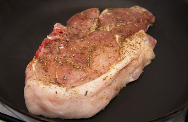 Fresh raw pork steak with spices roasting on frying pan