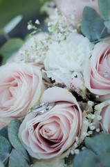 wedding rings on a bouquet of white roses