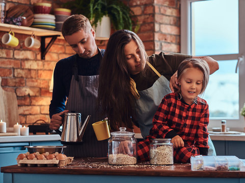 Mom Dad And Little Daughter Together Cooking Breakfast In Loft Style Kitchen.