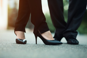 Closeup of businessman's and businesswoman's legs outside. Standing on the street.