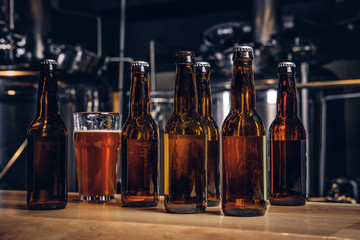 Bottles and glass of craft beer on wooden bar counter at the indie brewery.
