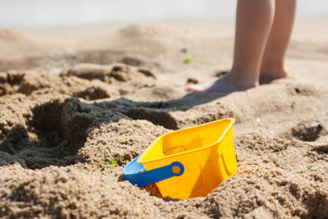 Fototapeta na wymiar Baby bucket on a sandy beach in the background