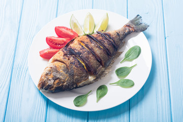 Fried fish dorado with lime , tomatoes and spinach