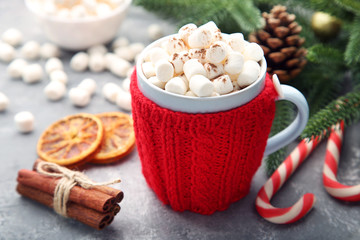 Cappuccino with marshmallow in mug, cinnamon and candy cane on wooden table