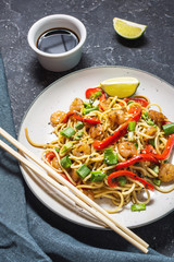 Stir fry noodles with vegetables and shrimps on stone background.