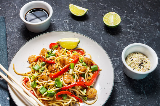 Stir fry noodles with vegetables and shrimps on stone background.