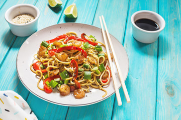 Stir fry noodles with vegetables and shrimps on wood background.