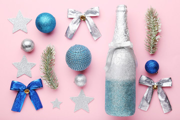 Champagne bottle with christmas decorations on pink background