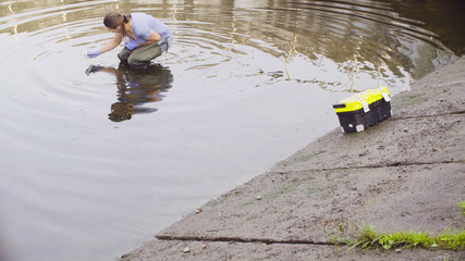 Woman ecologist measuring pH of the water in the city river. Damage appreciate to nature in an urban environment