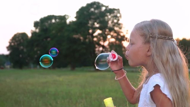 little blond girl blowing bubbles