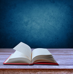 Open book on table in front of blue background