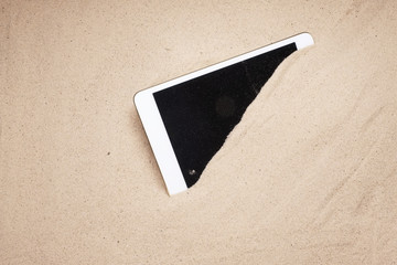 Tablet mobile screen display covered in sand at the beach damaged and lost insurance claim