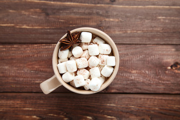 Fototapeta na wymiar Cappuccino with marshmallows in cup on brown wooden table