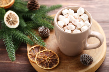 Cappuccino with marshmallows in cup and fir tree branches on wooden table