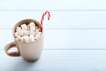 Cappuccino with marshmallows and candy cane on wooden table