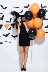 Young woman in halloween costume with balloons on white background