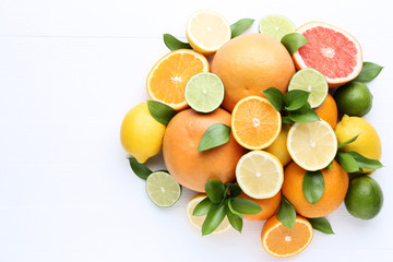 Citrus fruits with green leafs on white wooden table