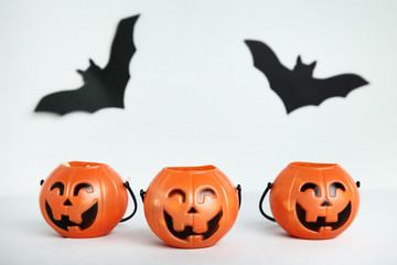 Halloween buckets with paper bats on grey background