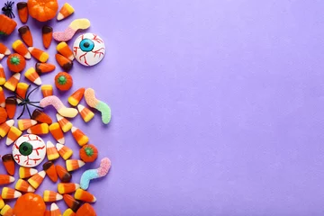 Rolgordijnen Halloween candy corns and pumpkins on purple background © 5second