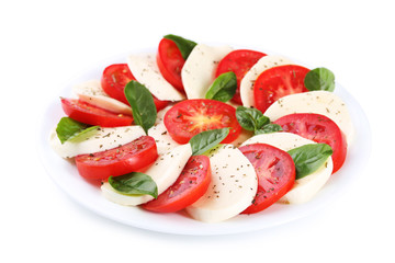 Mozzarella, tomatoes and basil leafs on plate isolated on white background