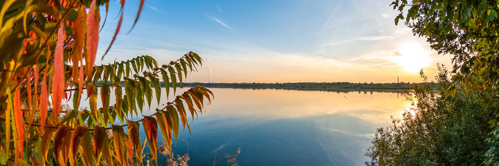 Farbenfroher Herbst Hintergrund, bunte Blätter vor blauem See Panorama