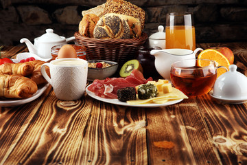 breakfast on table with bread buns, croissants, coffe and juice.