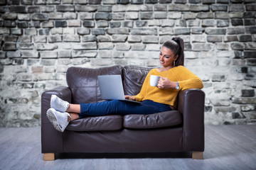 Lady sitting on a sofa relaxing and using a notebook