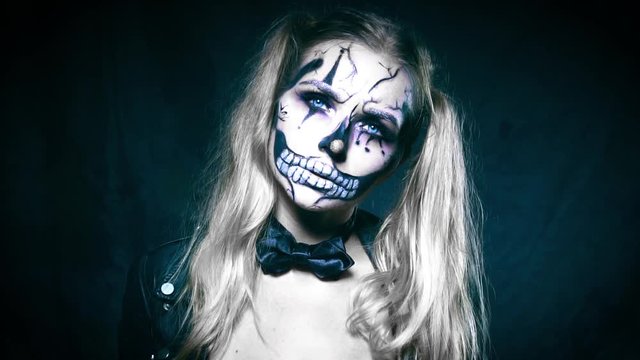 Closeup face of woman with creepy Halloween clown skull makeup looking into the camera. Creative, artistic, Halloween concept - video in slow motion