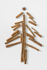 Christmas tree made of cinnamon sticks and anise. White background, flat lay, top view.