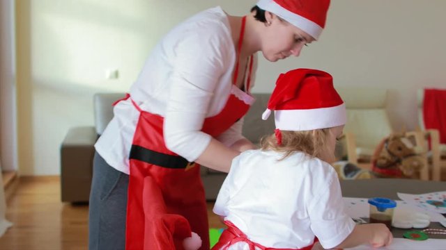 Young mother between 25 and 30 years old is painting with her children at round table in living room. Christmas period vacation