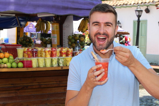 Man eating assorted fresh sliced fruits