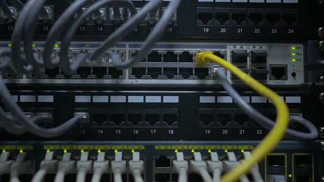 an IT engineer's hand plug in the network cable to the network switch