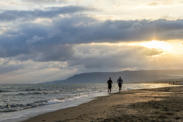 Naklejka premium couple running on the beach at sunrise