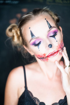 Closeup face of woman with creepy Halloween clown makeup looking into the camera. Creative, artistic, Halloween concept