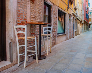 Fototapeta na wymiar Table and chairs in the street of Venice