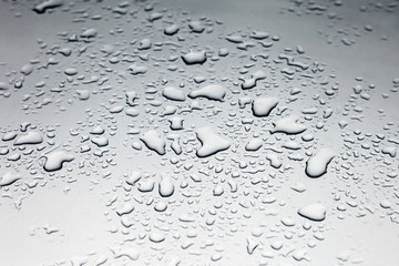 Raindrops lie on a metallic surface of gray color. Abstract picture for background and design. The drops of water lie on the surface.