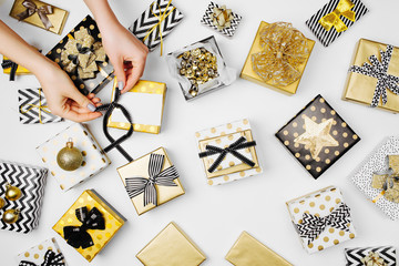 Women organising beautifully wrapped christmas presents on white background, view from above