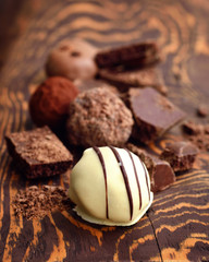 Handmade chocolate candies and pieces of chocolate on wooden background