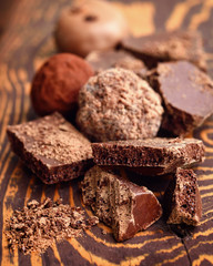 Handmade chocolate candies and pieces of chocolate on wooden background
