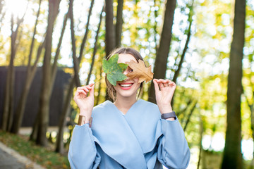 Portrait of a beautiful woman with colorful leaves outdoors during the autumn in the forest