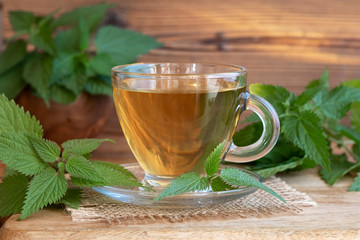 A cup of nettle tea with fresh stinging nettles