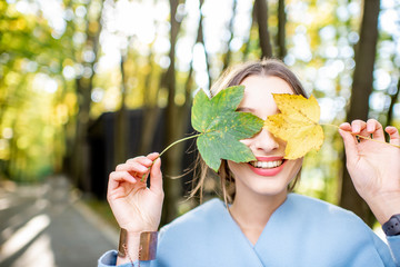 Close-up portrait of a beautiful woman with colorful leaves outdoors during the autumn in the forest