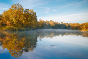 Symmetry reflection on the autumn river. Sunrise.