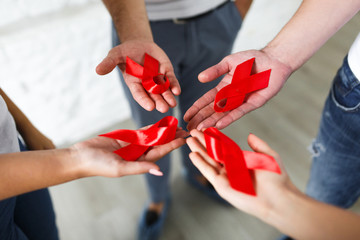 Group of young multiracial woman with red ribbons in hands are struggling against HIV/AIDS. AIDS awareness concept. - obrazy, fototapety, plakaty