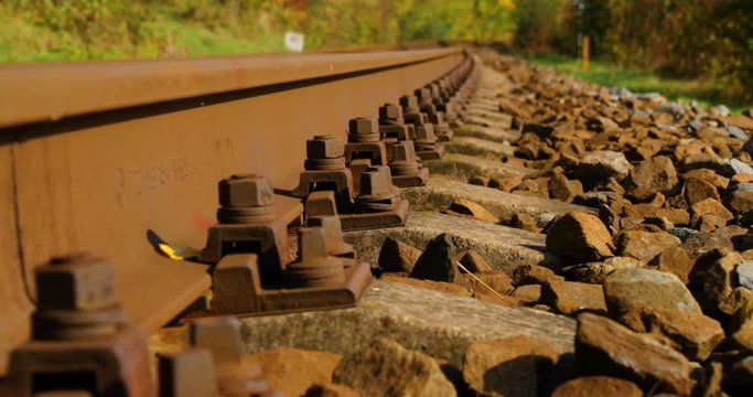 Slow Close-up view of security bolts at train tracks in slow camera movement forward outside the city during a sunny day in autumn.