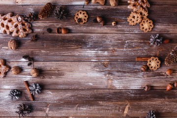 Christmas decor and place for text. Cookies, cinamon branches and cones make a circle on old wooden table